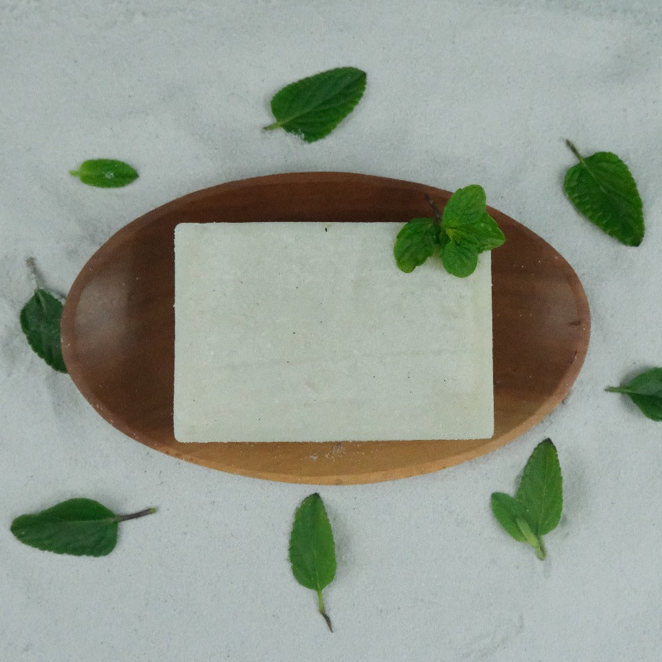 A Peppermint Pumice Soap on a wooden soap dish, with peppermint leaves as decoration