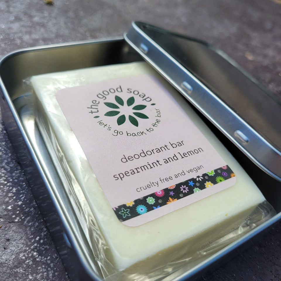 A natural solid deodorant bar in a compostable bag, in an open rectangle aluminium storage / travel tin.