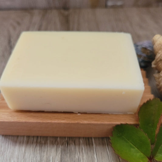 A Cocoa Butter and Rose Soap & Shampoo Bar with no packaging, on a wooden soap dish