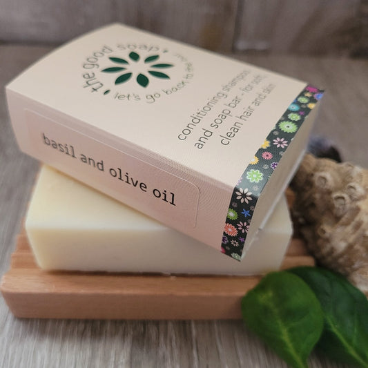 A Basil and Olive Oil Soap and Shampoo Bar on a wooden soap dish, in packaging