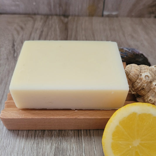 A Citrus Soap & Shampoo Bar with no packaging, on a wooden soap dish