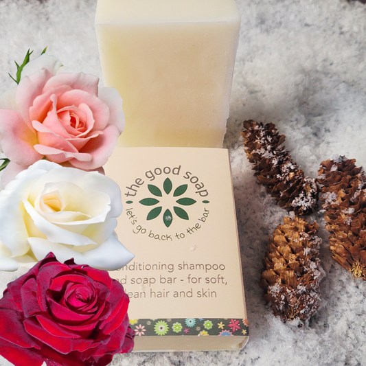 Bar of soap with packaging labeled 'the good soap' surrounded by roses and pinecones on a snowy background