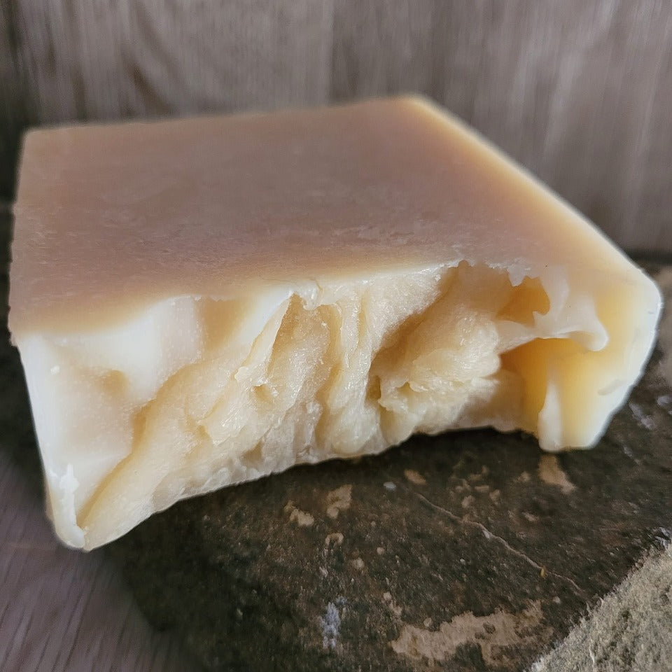 A plain unwrapped Goat Milk Soap on a stone