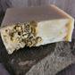 Goat Milk and Chamomile Soap on stone. The soap is decorated with dried chamomile flowers.