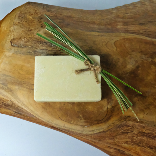 A natural deodorant bar in Lemongrass scent on a wooden background. In the picture is also a bunch of lemongrass for decoration