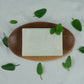 A Peppermint Pumice Soap on a wooden soap dish, with peppermint leaves as decoration