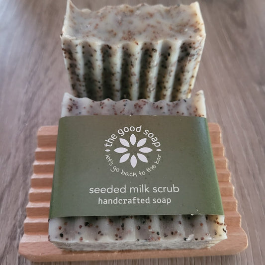 A Good Soap seeded milk scrub soap on a wooden soap dish, on a wooden background