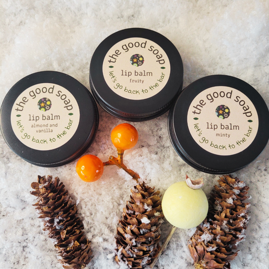 Three lip balm containers with decorative elements on a textured surface