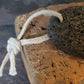 A Volcanic Lava Foot Stone showing the hanging string, on a brick background