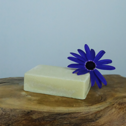 A natural floral deodorant bar on a wooden background with a pretty purple flower