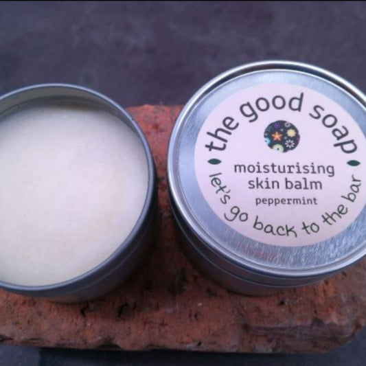 A tin of Peppermint Skin Balm on a brick background