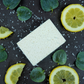 A Lemon eucalyptus salt soap on a slate background, surrounded by lemon slices and eucalyptus leaves 