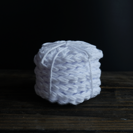 Hand crocheted white cotton reusable face cleansing disks. In a stack of 6 on a wooden background.