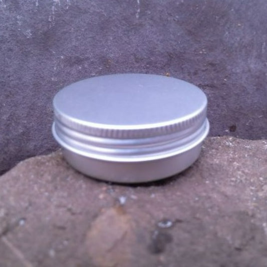 A small round aluminium screwtop tin on a stone background