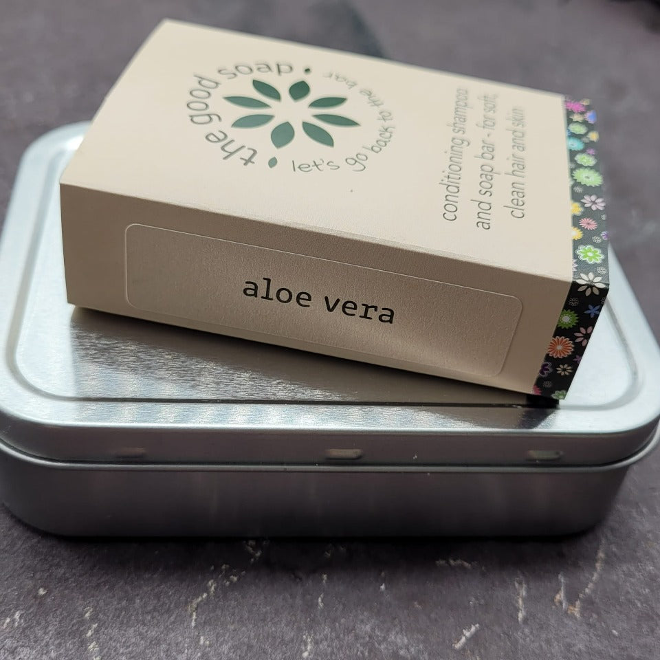 An Aloe Vera soap and shampoo bar on top of an aluminium storage or travel tin